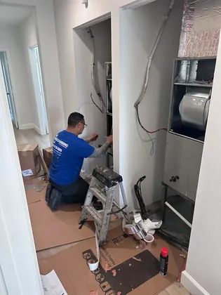 Direct Cooling technician wiring a new air handler in a hallway closet
