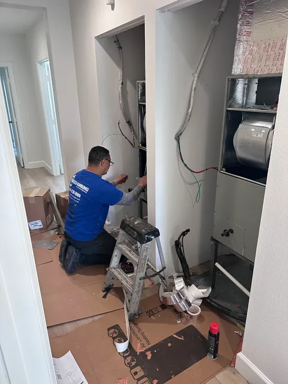 A Direct Cooling technician connects wiring on one of two new air handlers being installed in side by side hallway closets. Direct Cooling technician wiring a new air handler in a hallway closet