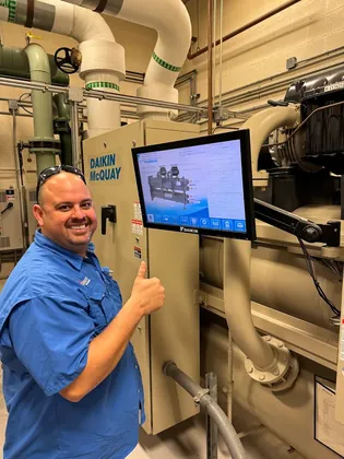Direct Cooling technician giving a thumbs up beside a Daikin chiller control screen