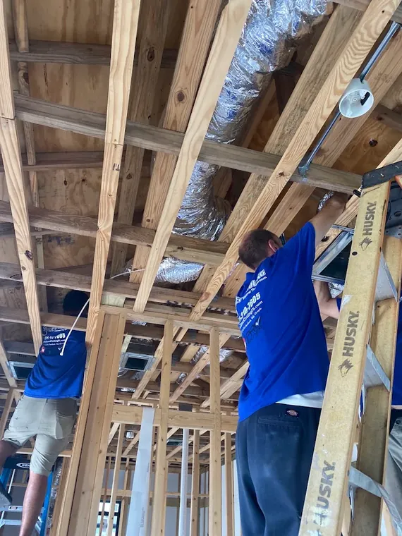 Direct Cooling technicians running insulated flex duct through open ceiling framing