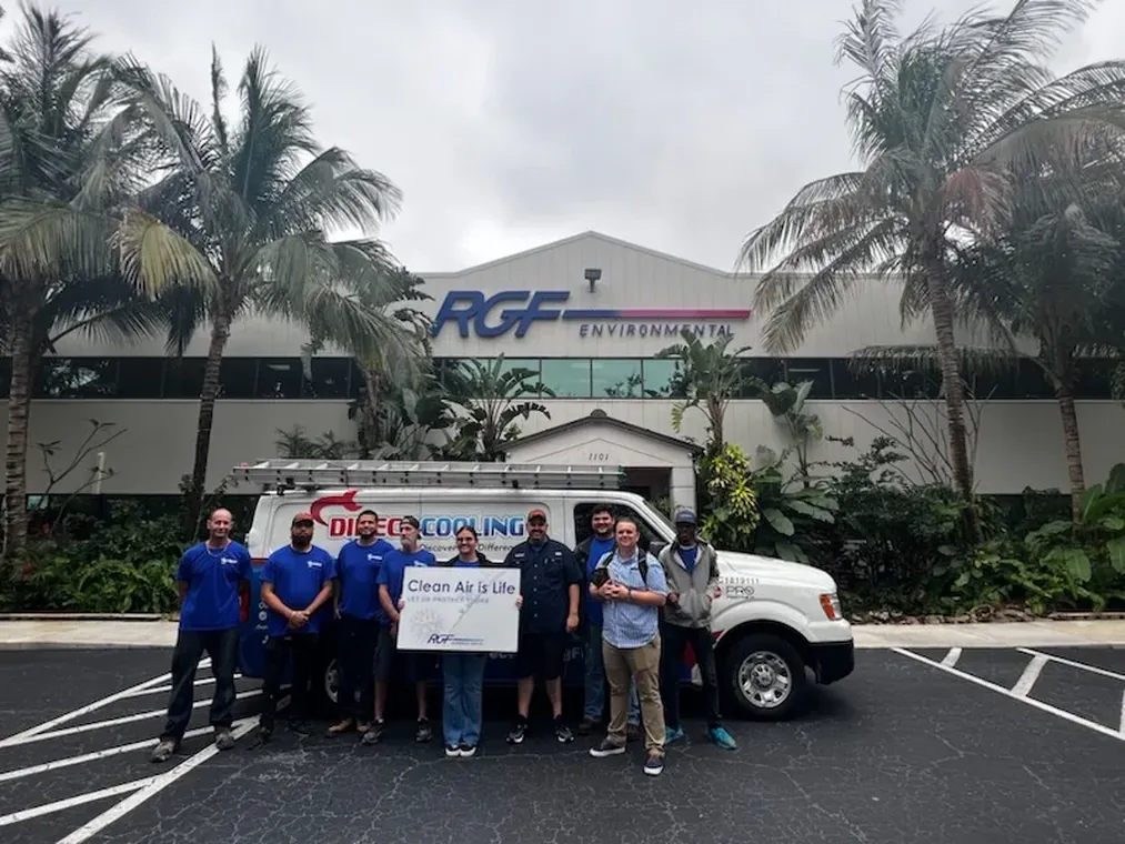 The Direct Cooling team gathered with a service van outside RGF Environmental, holding a Clean Air is Life sign. The Direct Cooling team standing in front of a company van at RGF Environmental