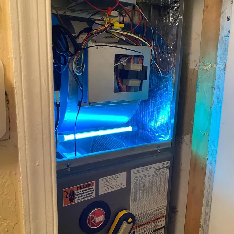 UV germicidal light glowing blue inside an open Rheem air handler